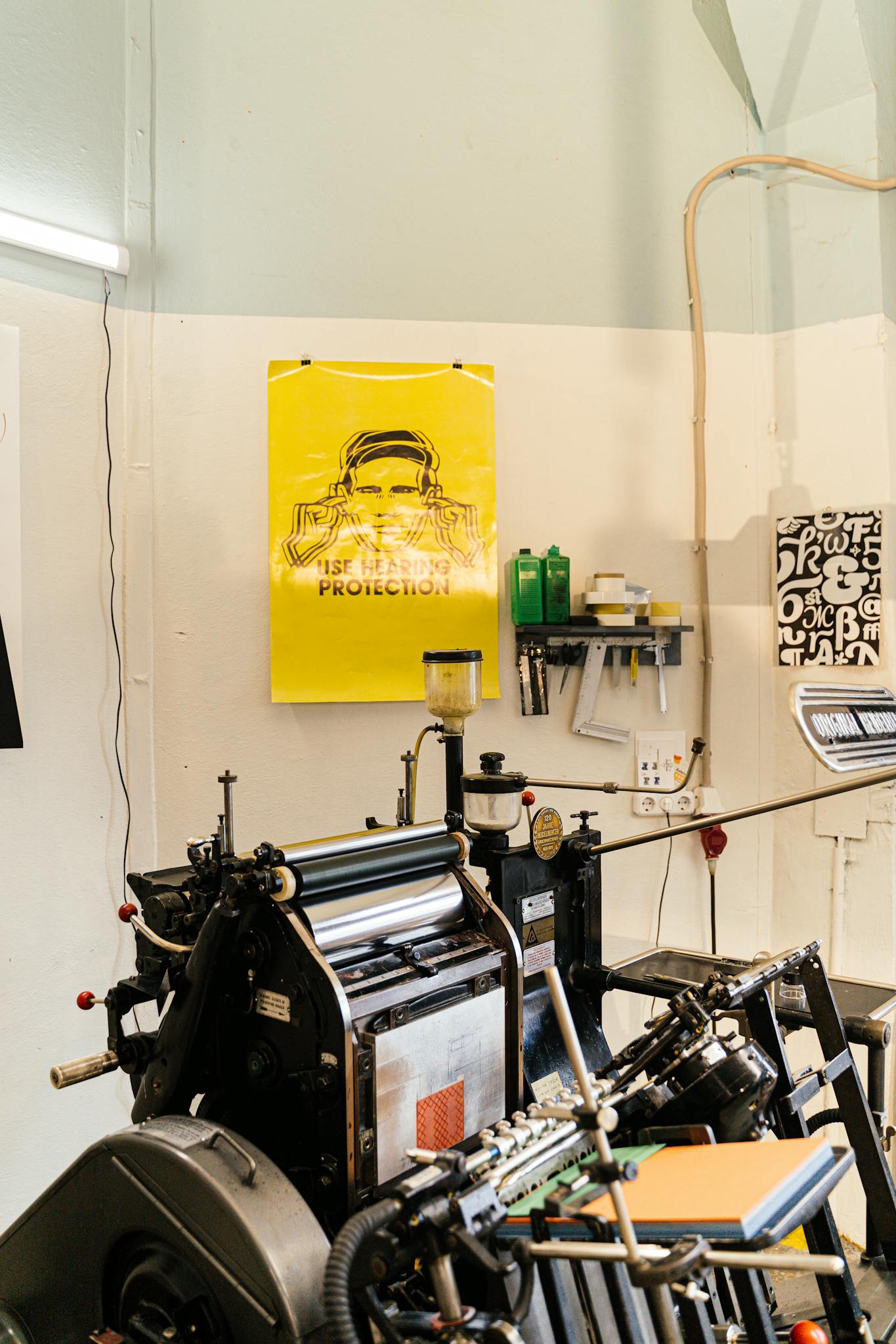 A detailed view of a professional printing press setup in a studio, highlighting equipment and posters.
