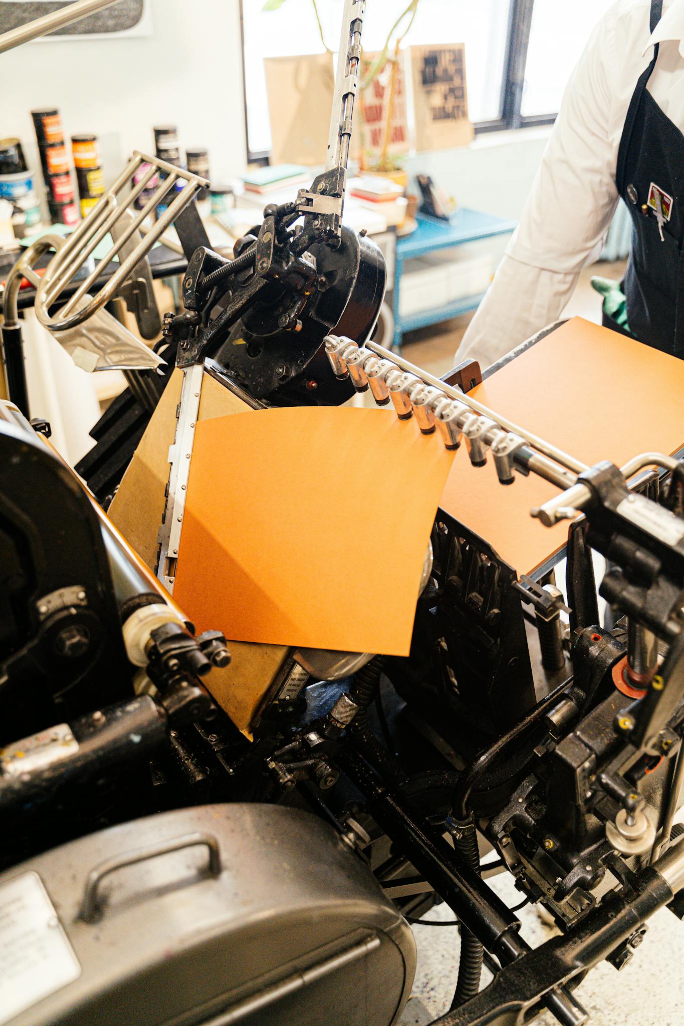 Close-up of a vintage printing press with orange paper, highlighting industrial craftsmanship.