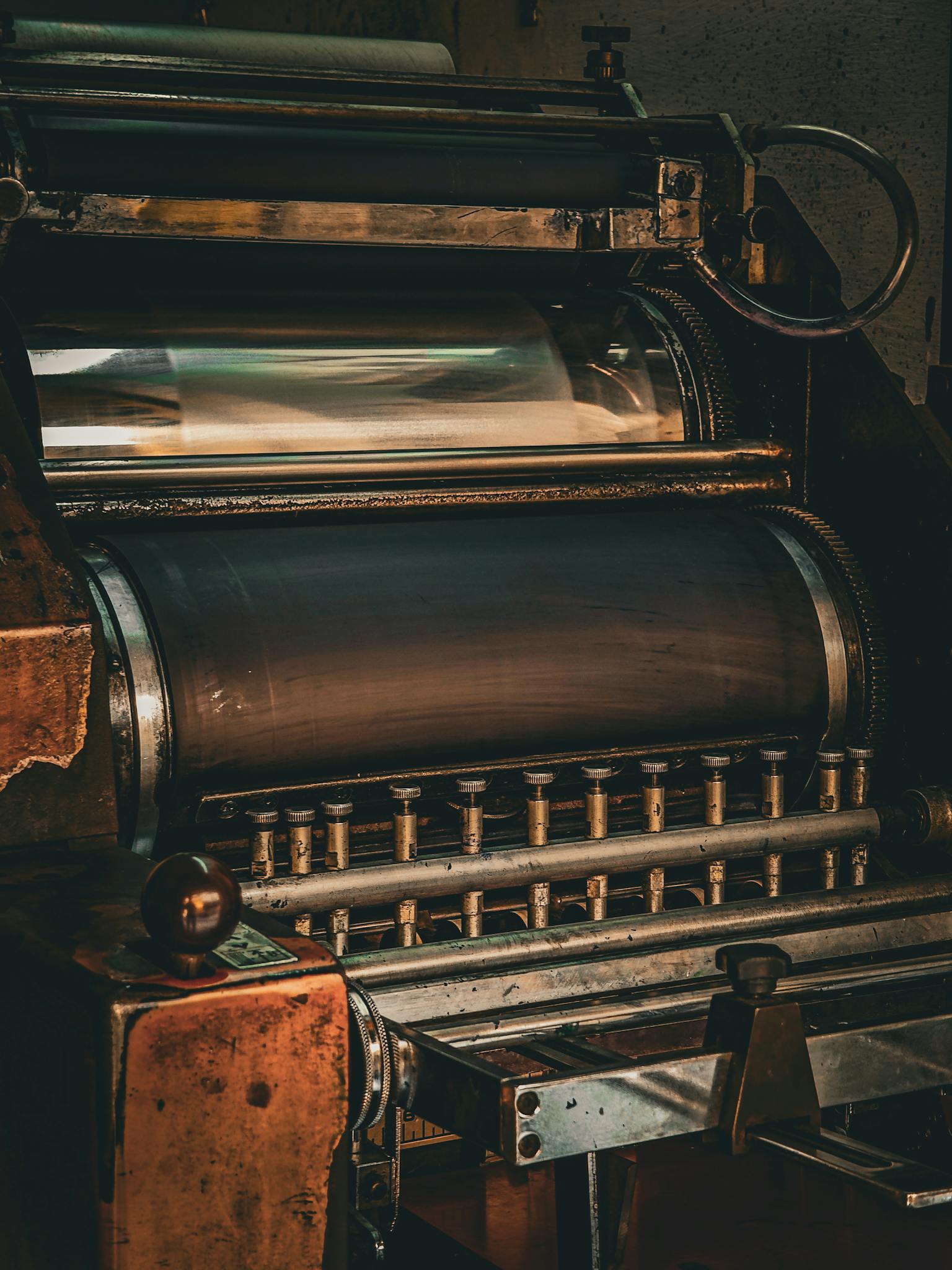 Close-up view of an old printing press showcasing rollers and gears, emphasizing industrial mechanics.