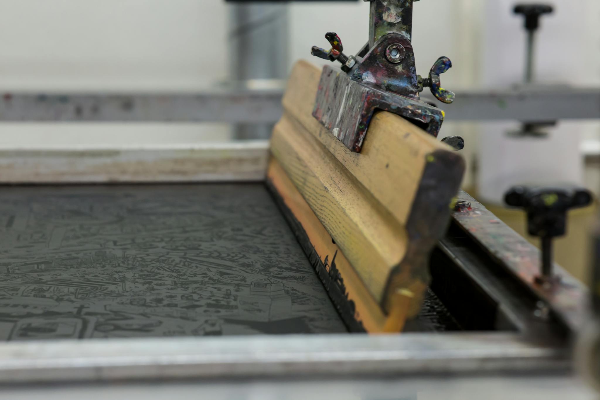 Detailed view of a screen printing setup with a wooden squeegee in Luzern, Switzerland.